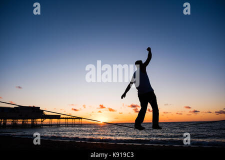 Aberystwyth Wales UK, Donnerstag, den 21. September 23017 UK Wetter: Am Vorabend der Herbst-tagundnachtgleiche, Jesse stecken, ein 3. Jahr Student Studium der Astrophysik an der Universität Aberystwyth, Praktiken seiner Slack-line Fähigkeiten, wie die Sonne über dem Meer setzt auf aberystwyth an der Küste von West Wales Photo Credit: Keith Morris/Alamy leben Nachrichten Stockfoto