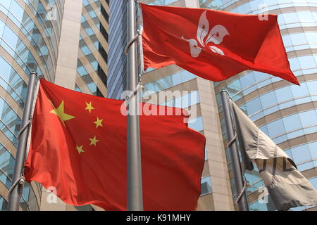 China und Hongkong Fahnen wehen im Wind mit Glas Gebäude Hintergrund Stockfoto