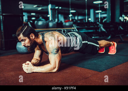 Bemuskelt junger Mann Sport Verschleiß und tun Ganzkörperstütz während des Trainings auf dem Boden im Loft Innenraum Stockfoto