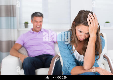 Reifer Mann zu schreien Der frustrierte Frau sitzt auf Stuhl Stockfoto