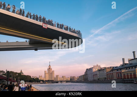Menschen auf Moskvoretskaya Embankment und schwimmende Brücke von zaryadye Park, mit Kotelnicheskaya Damm Gebäude im Hintergrund, Moskau, Russland Stockfoto