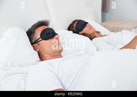 Portrait von Gereift Paar bequem schlafen auf Bett mit Augenmaske Stockfoto