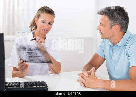 Ärztin untersuchen die X-ray von einem männlichen Patienten in der Klinik Stockfoto