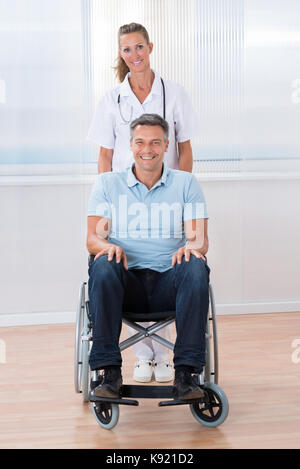 Gerne Ärztin bei männlichen Patienten im Rollstuhl Stockfoto