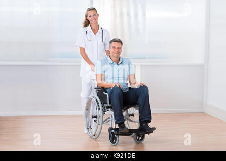 Gerne Ärztin bei männlichen Patienten im Rollstuhl Stockfoto