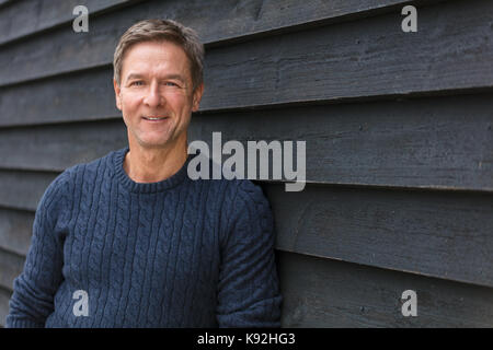 Portraitfotos eines attraktiven, erfolgreich und glücklich lächelnde Menschen als Mann mittleren Alters außerhalb trägt einen blauen Pullover Stockfoto