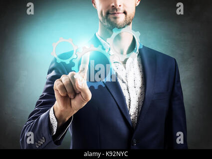 Geschäftsmann Druck auf die Gruppe der Zahnräder. Stockfoto