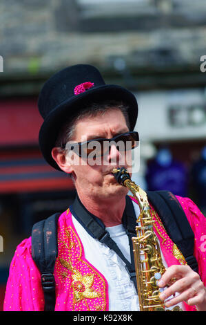 Männliche Musiker aus dem passgang Band Saxophon am Grassmarket während des Edinburgh International Fringe Festival, Schottland, Großbritannien Stockfoto