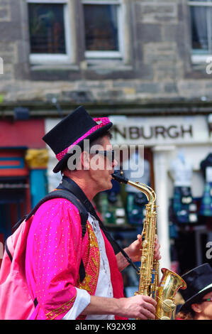 Männliche Musiker aus dem passgang Band Saxophon am Grassmarket während des Edinburgh International Fringe Festival, Schottland, Großbritannien Stockfoto