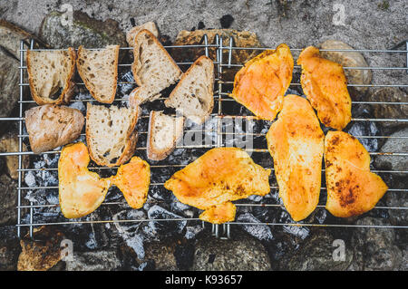 Huhn und Brot auf hausgemachte improvisierte BBQ Grill. Das Huhn und Brot auf Kohle, Feuer, briketts BBQ Grill im Sand mit Felsen und s Stockfoto