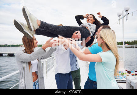 Gruppe der glücklichen Freunde am Strand, Mann warf eine glückliche Frau. Stockfoto