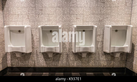 Vier Urinale in einer Reihe, durch interessante Fliesen umgeben, die in der männlichen Toiletten von JD Wetherspoon Pub Restaurant (wetherspoons), Stamford, England, UK. Stockfoto