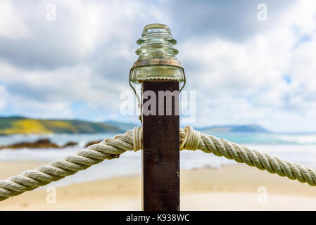 Seil Zaun auf hölzernen Säule mit Glas Lampe am Strand. Einem Holzzaun mit Seil inlays an einem Sandstrand am Atlantik im Norden Spaniens. Stockfoto