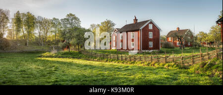 Altes Bauernhaus und traditionellen roundpole Zaun in einer ländlichen Landschaft am Dorf Stensjo durch in Smaland, Schweden, Skandinavien Stockfoto