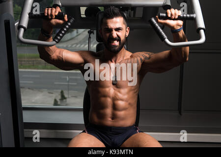 Gut aussehend muskuläre Fitness Bodybuilder schwere Übung für Brust auf Rechner mit Kabel In der Turnhalle Stockfoto