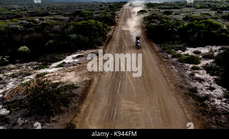 Landschaft mit Mann, Cafe Racer Motorrad entlang der staubigen Piste. Stockfoto