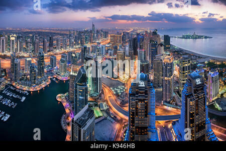 Luftaufnahme von das Stadtbild von Dubai, Vereinigte Arabische Emirate bei Dämmerung, mit beleuchteten Wolkenkratzer und den Jachthafen im Vordergrund. Stockfoto