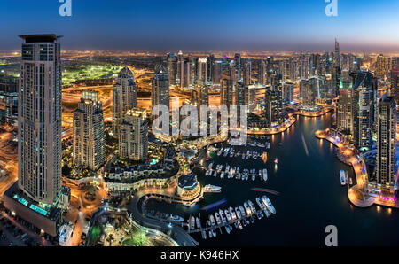 Luftaufnahme von das Stadtbild von Dubai, Vereinigte Arabische Emirate bei Dämmerung, mit beleuchteten Wolkenkratzer und den Jachthafen im Vordergrund. Stockfoto