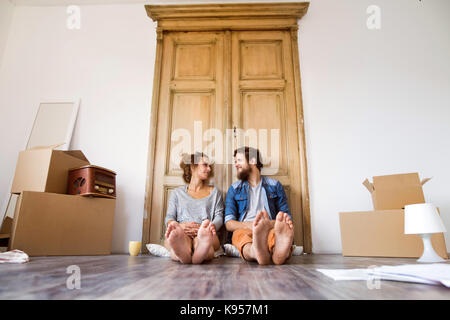 Junges Ehepaar Umzug in neues Haus, auf dem Boden liegend in der Nähe von Kartons, ausruhen. Stockfoto