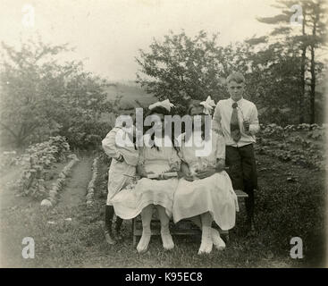 Antike c 1920 Foto, zwei Mädchen in weißen Holding blättert, möglicherweise auf den Tag der Erstkommunion; ein Mädchen trägt ein Kreuz Anhänger. Sie werden durch zwei Jungen flankiert. Lage unbekannt, wahrscheinlich Neu England. Quelle: original Foto. Stockfoto