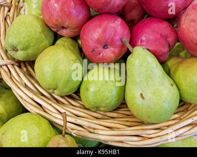 Rote und grüne Birnen in Weidenkorb auf dem Markt Stockfoto