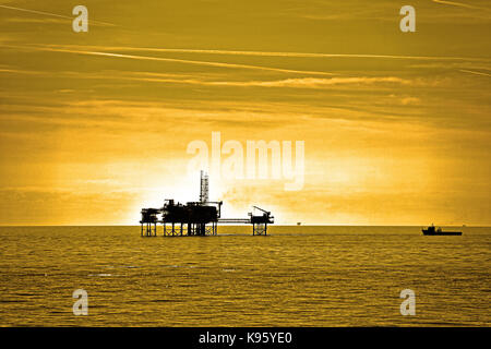 Nordsee Öl Gas Plattformen rigs Stationen gegen warm sky Silhouette Stockfoto