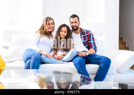 Junge Eltern Standortwahl auf der Couch mit Ihrer Tochter Stockfoto