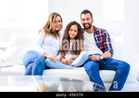 Junge Eltern Standortwahl auf der Couch mit Ihrer Tochter Stockfoto