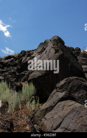 Große basaltischen Boulder ist durch den strahlend blauen Himmel außerhalb von Albuquerque, New Mexico. Boulder ist in Boca Negra Canyon im Pueblo Indian C gefunden Stockfoto