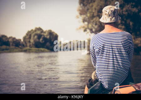 Nachdenklicher junger Mann auf Boot und Blick auf die schöne Landschaft im Sommer Camp Ferien Stockfoto