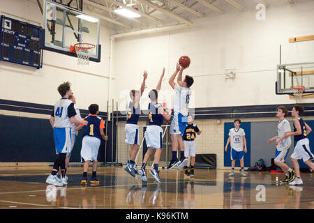 Jugendliche Junge springt ein Fuß über dem Boden sein Schuss in der Schule Basketball Spiel zu machen. St. Paul Minnesota MN USA Stockfoto