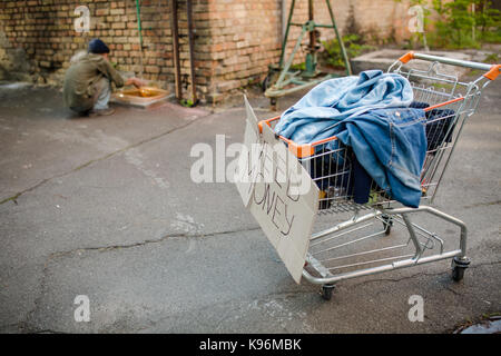 Auf der Vorderseite Warenkorb anzeigen mit Sachen oh Tramp, alter Mann, Waschen der Hände im Hintergrund. Stockfoto