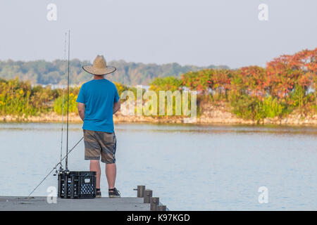 Junge Mann trägt einen Strohhut Fische aus dem Pier in Orillia Ontario Kanada auf einem schönen Anfang Herbst Abend. Stockfoto