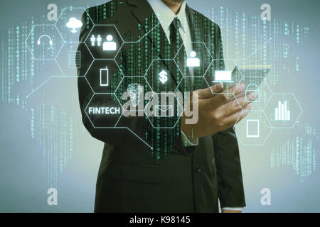 Geschäftsmann mit fintech Symbol und Internet der Dinge mit Matrix Code Hintergrund, Investitionen und finanzielle internet technologie Konzept. Stockfoto