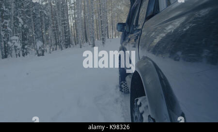 Jeep reitet auf dem Schnee in den Wald Nahaufnahme. Stockfoto