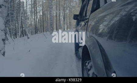 Jeep reitet auf dem Schnee in den Wald Nahaufnahme. Stockfoto