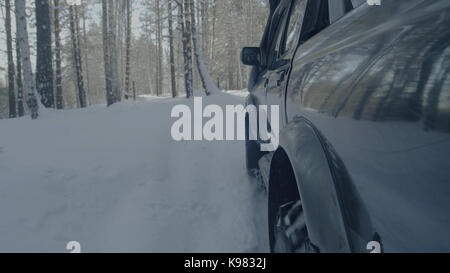 Jeep reitet auf dem Schnee in den Wald Nahaufnahme. Stockfoto