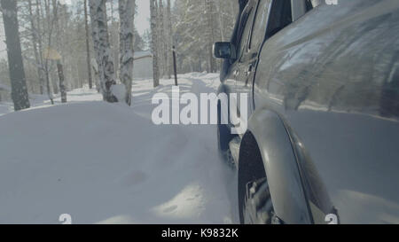 Jeep reitet auf dem Schnee in den Wald Nahaufnahme. Stockfoto