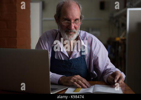Portrait Goldschmied schreiben in Buch in der Werkstatt Stockfoto