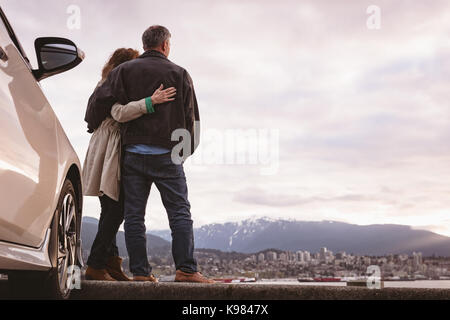 Senior Paar umarmen einander in der Nähe des Auto Stockfoto