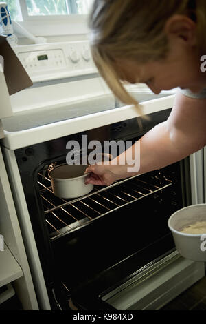 Frau setzen Kuchen in den Backofen in der Küche Stockfoto
