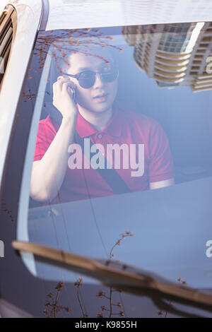 Mann über sein Handy im Auto Stockfoto