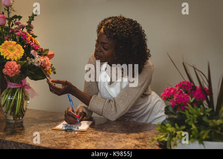 Weibliche unter Auftrag auf Handy im Blumenladen Blumengeschäft Stockfoto