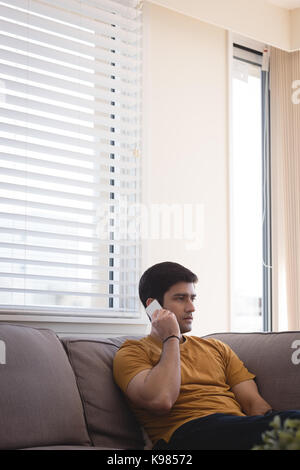 Mann Gespräch am Handy im Wohnzimmer zu Hause Stockfoto