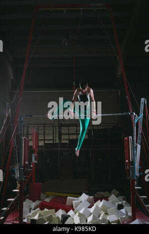 Männliche gymnast Gymnastik üben auf der horizontalen Leiste in der Turnhalle Stockfoto