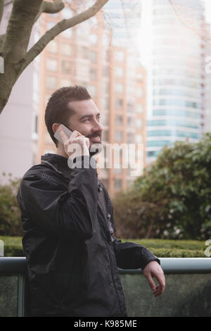 Junger Mann Gespräch am Handy im Garten Stockfoto