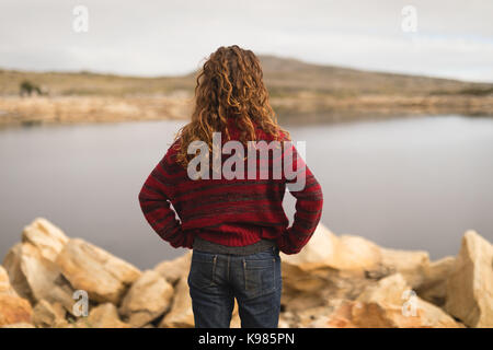 Rückansicht der Frau, die in der Nähe von Lakeside Stockfoto