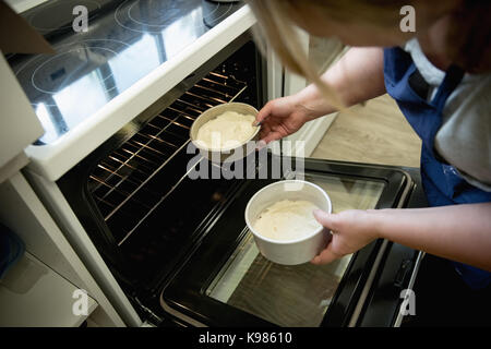 Frau setzen Kuchen in den Backofen in der Küche Stockfoto