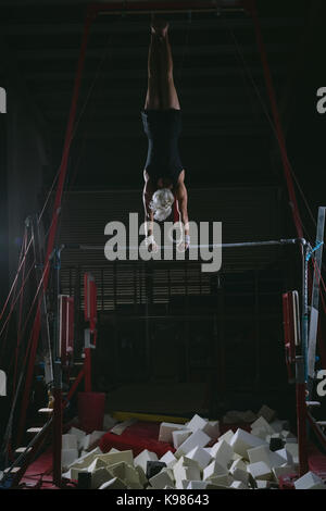 Männliche gymnast Gymnastik üben auf der horizontalen Leiste in der Turnhalle Stockfoto