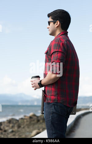 Mann mit Kaffee Tasse in der Nähe von Strand an einem sonnigen Tag Stockfoto